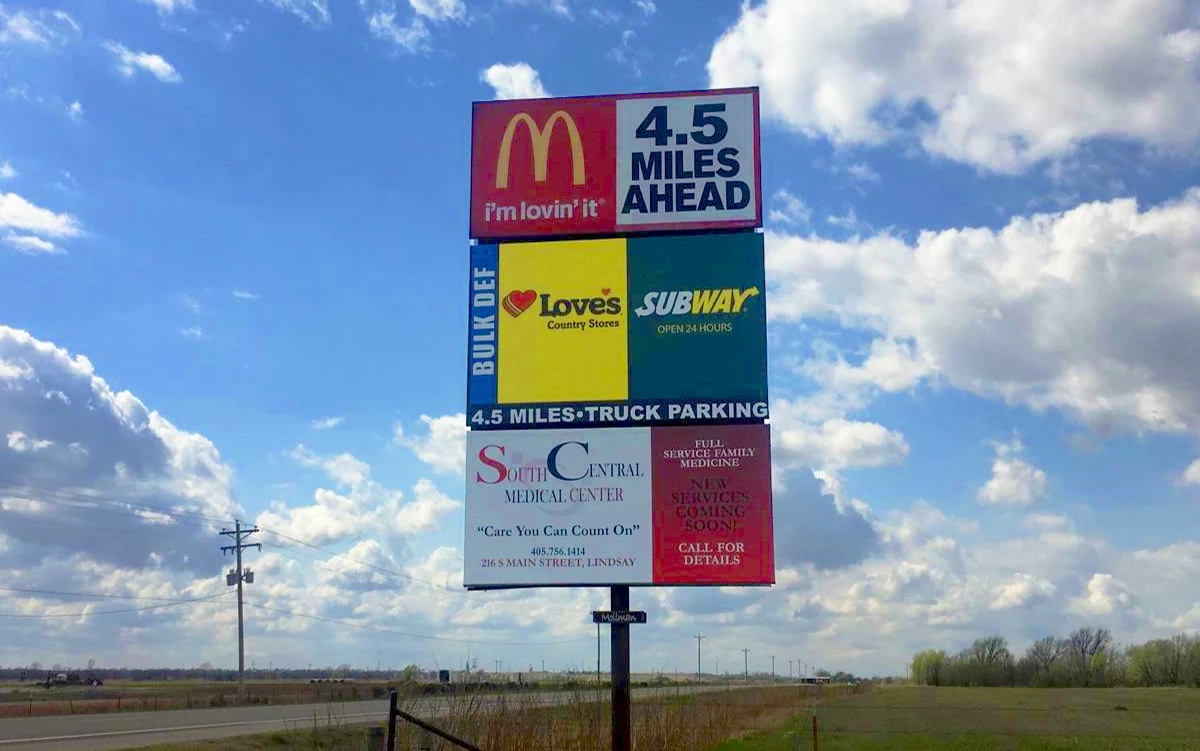 Highway sign with food and services logos.